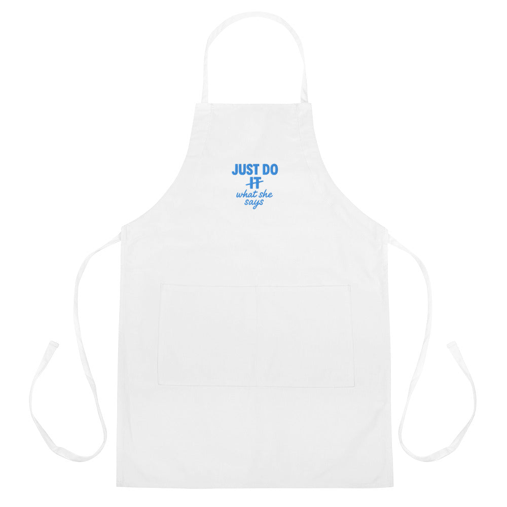 White apron with Just Do What She Says printed on it.