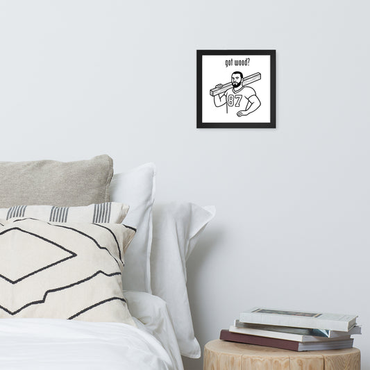 Framed artwork on a wall above a bed with pillows and books.
