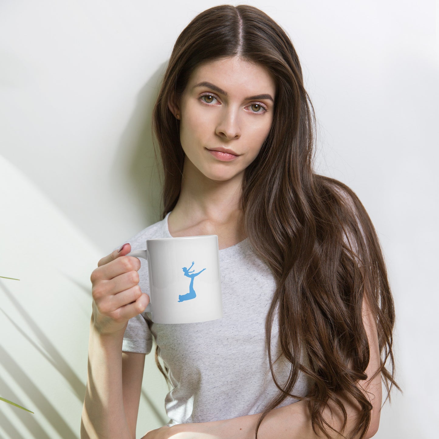 Woman holding a white mug with a blue design against a plain background