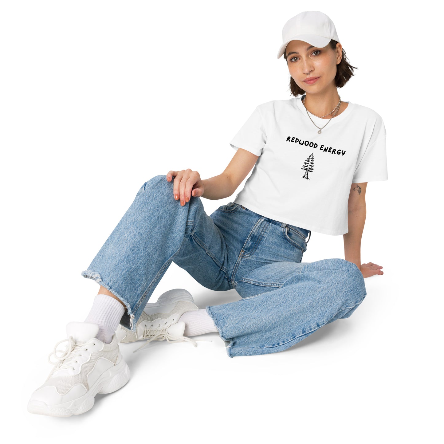 Person wearing a white t-shirt with text and graphics, blue jeans, and white sneakers on a white background