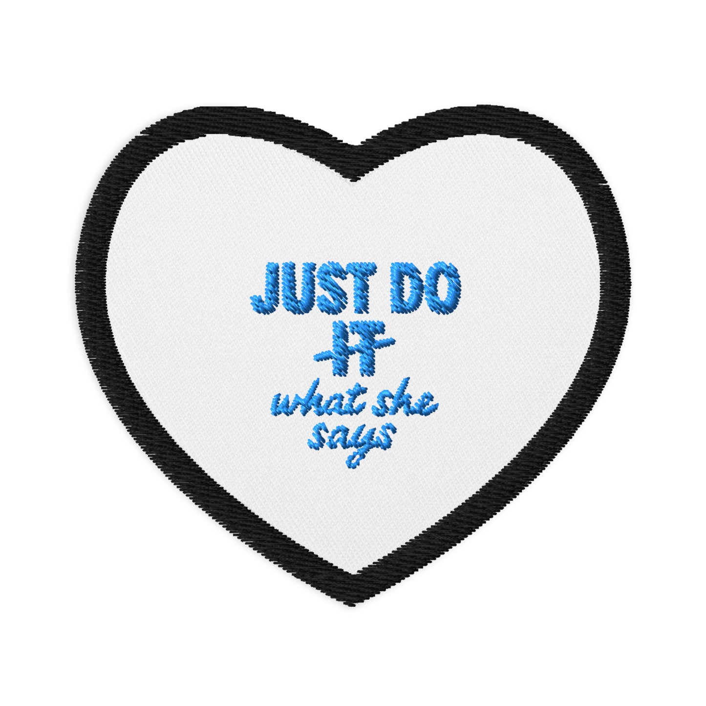 White heart patch with black outline and Just Do What She Says embroidered on the middle in light blue.