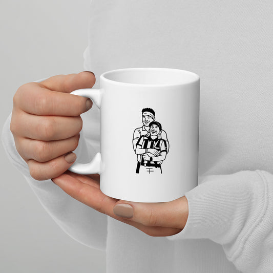 White mug with a black and white illustration held by a hand against a gray background
